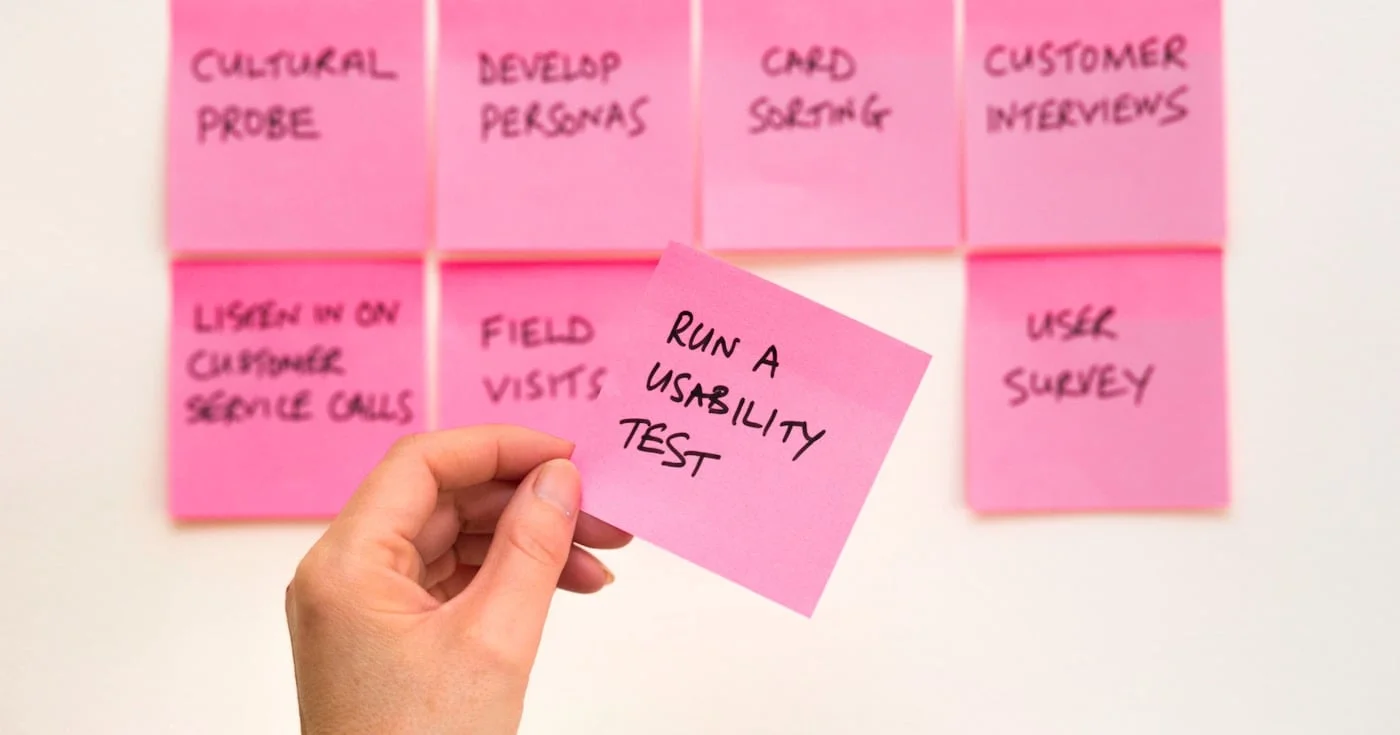 UX researcher holding a sticky note that says run a usability test